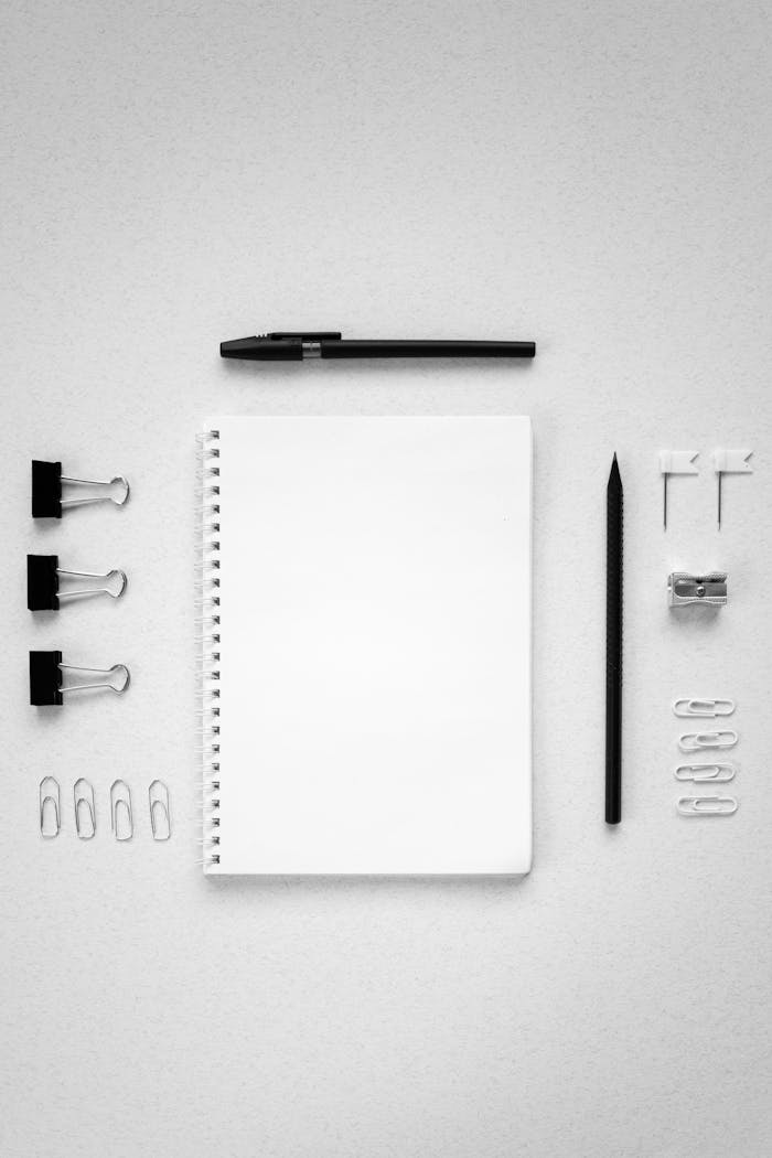 Top view of office supplies arranged neatly on a white surface for a clean and minimalist look.